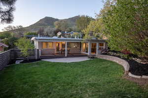 Rear view of property with a patio area, a mountain view, a yard, and fence