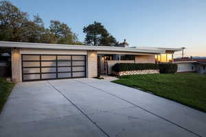 Contemporary home with concrete driveway, a front yard, and brick siding
