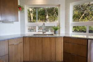 Kitchen with dishwasher, light stone countertops, a sink, and tasteful backsplash