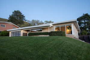View of front of property featuring an attached garage, a front lawn, and brick siding
