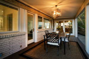 Sunroom with an inviting chandelier, outdoor dining space, and brick wall