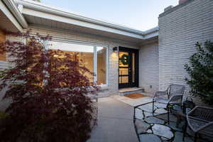 View of exterior entry featuring brick siding and a patio area