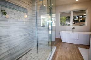 Bathroom featuring a freestanding bath, a stall shower, recessed lighting, and wood finished floors