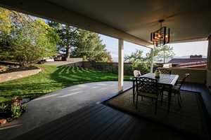 Deck with a lawn, fence, and outdoor dining space