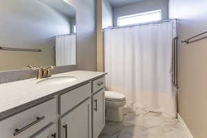 Bathroom featuring vanity, a shower with shower curtain, toilet, and marble finish floor