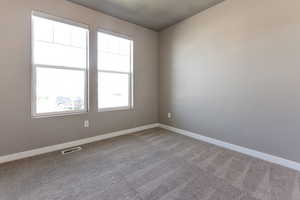 Carpeted spare room featuring baseboards and visible vents
