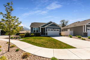 Craftsman-style home featuring a front lawn, fence, board and batten siding, concrete driveway, and an attached garage