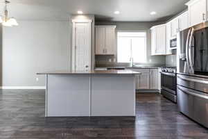 Kitchen featuring a center island, recessed lighting, dark wood-type flooring, a sink, and stainless steel appliances