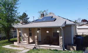View of front facade with a shingled roof, fence, a chimney, and solar panels