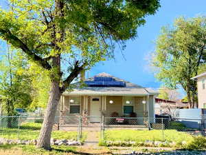 Bungalow-style Main-lvl-living house featuring a gate, a fenced front yard, covered porch, and solar panels