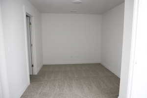 Carpeted spare room featuring baseboards and visible vents
