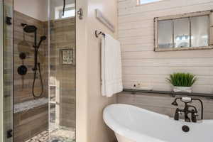 Bathroom featuring a sink, a freestanding tub, wooden walls, and a shower stall