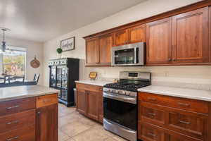 Kitchen featuring light countertops, light tile patterned floors, decorative light fixtures, and stainless steel appliances