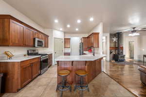 Kitchen with a wood stove, a breakfast bar area, light countertops, stainless steel appliances, and a peninsula