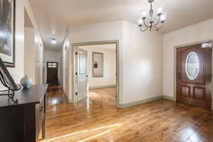 Foyer with baseboards, visible vents, light wood-style flooring, and a notable chandelier