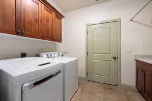 Clothes washing area with baseboards, cabinet space, and independent washer and dryer
