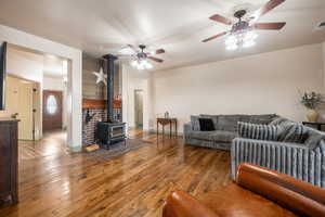 Living area featuring baseboards, ceiling fan, a wood stove, and hardwood / wood-style floors