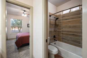 Bathroom with bathing tub / shower combination, ceiling fan, toilet, and a wealth of natural light