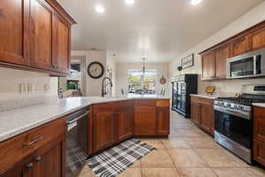 Kitchen featuring appliances with stainless steel finishes, a sink, light countertops, a peninsula, and light tile patterned flooring