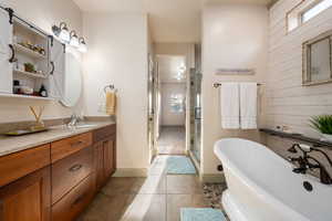 Bathroom featuring vanity, a freestanding bath, a wealth of natural light, and a shower stall