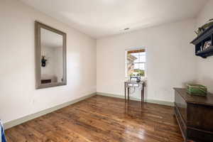 Unfurnished room with baseboards, wood finished floors, and visible vents