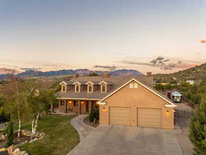 View of front of house with a porch, a lawn, fence, a mountain view, and concrete driveway