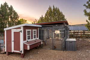 Outdoor structure at dusk with exterior structure, fence, and an outbuilding