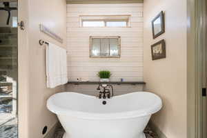 Bathroom with wooden walls, baseboards, and a soaking tub