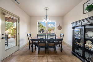 Dining space with visible vents, baseboards, a chandelier, and a healthy amount of sunlight
