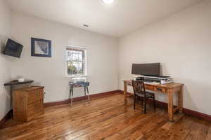Office space featuring baseboards, visible vents, and hardwood / wood-style floors