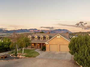 View of front facade featuring an attached garage, a mountain view, a chimney, concrete driveway, and covered porch