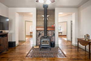 Living area featuring a ceiling fan, baseboards, a wood stove, and hardwood / wood-style floors
