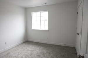 Carpeted empty room with baseboards and visible vents