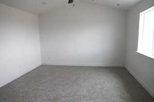 Unfurnished room featuring carpet floors, baseboards, a ceiling fan, and lofted ceiling