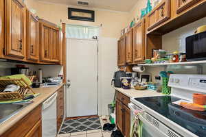 Kitchen with white appliances, brown cabinets, ornamental molding, and light countertops
