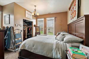 Bedroom featuring a chandelier, access to exterior, carpet, visible vents, and a closet