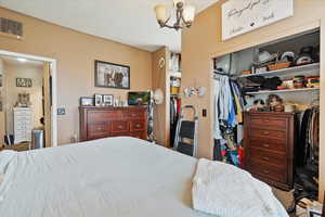 Bedroom with visible vents, a notable chandelier, and a closet