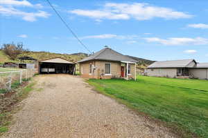 Bungalow-style house featuring driveway, an outbuilding, a detached carport, fence, and a front lawn