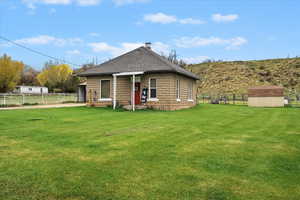 Back of property with a lawn, a fenced backyard, roof with shingles, and a storage unit