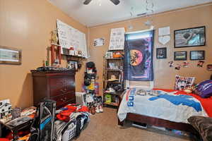 Carpeted bedroom with ceiling fan, visible vents, and radiator