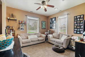 Living room with visible vents, a ceiling fan, plenty of natural light, and carpet flooring