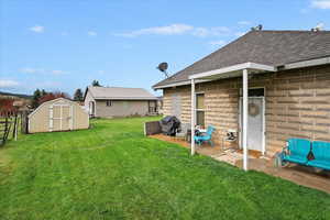 View of yard featuring a patio area, a shed, an outbuilding, and fence