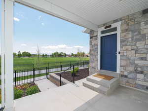 Entrance to property featuring fence, a lawn, and stone siding
