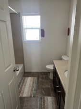 Full bathroom with vanity, baseboards, shower / bath combination, and toilet