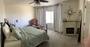 Bedroom with baseboards, carpet, ceiling fan, and a fireplace