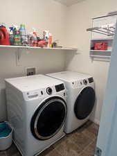 Laundry area with dark tile patterned flooring, laundry area, and washer and clothes dryer