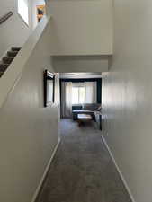 Corridor with baseboards, carpet flooring, a high ceiling, and stairway