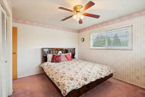 Bedroom with carpet floors, a textured ceiling, ceiling fan, and a closet
