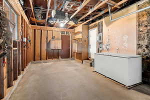 Unfinished basement with white refrigerator