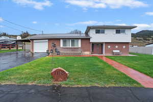 Split level home featuring a garage, a front yard, aphalt driveway, and brick siding